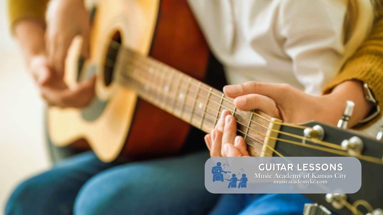 a person teaching another person how to play the guitar